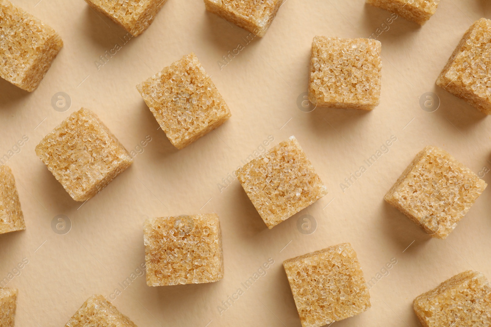 Photo of Brown sugar cubes on beige background, top view