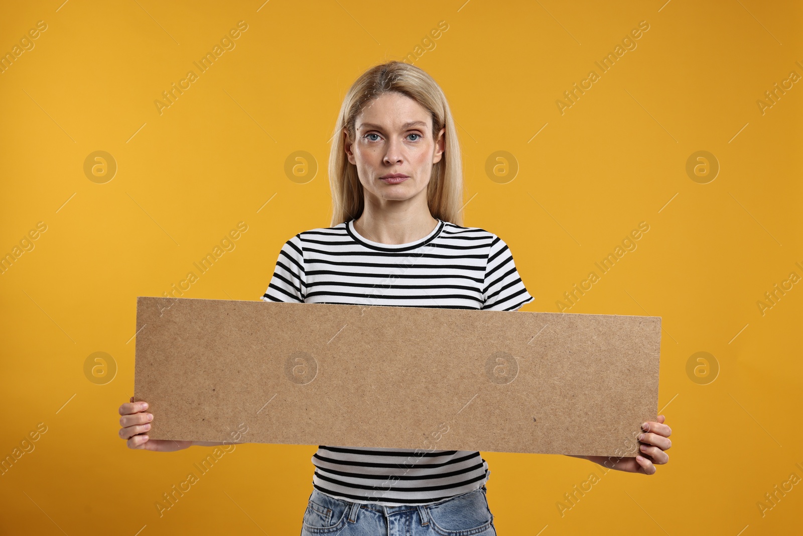 Photo of Woman holding blank cardboard banner on orange background, space for text