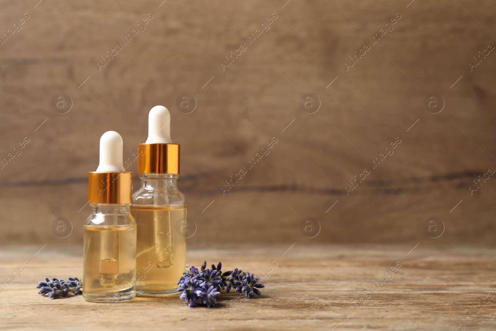 Photo of Beautiful lavender flowers and natural essential oil on wooden table. Space for text