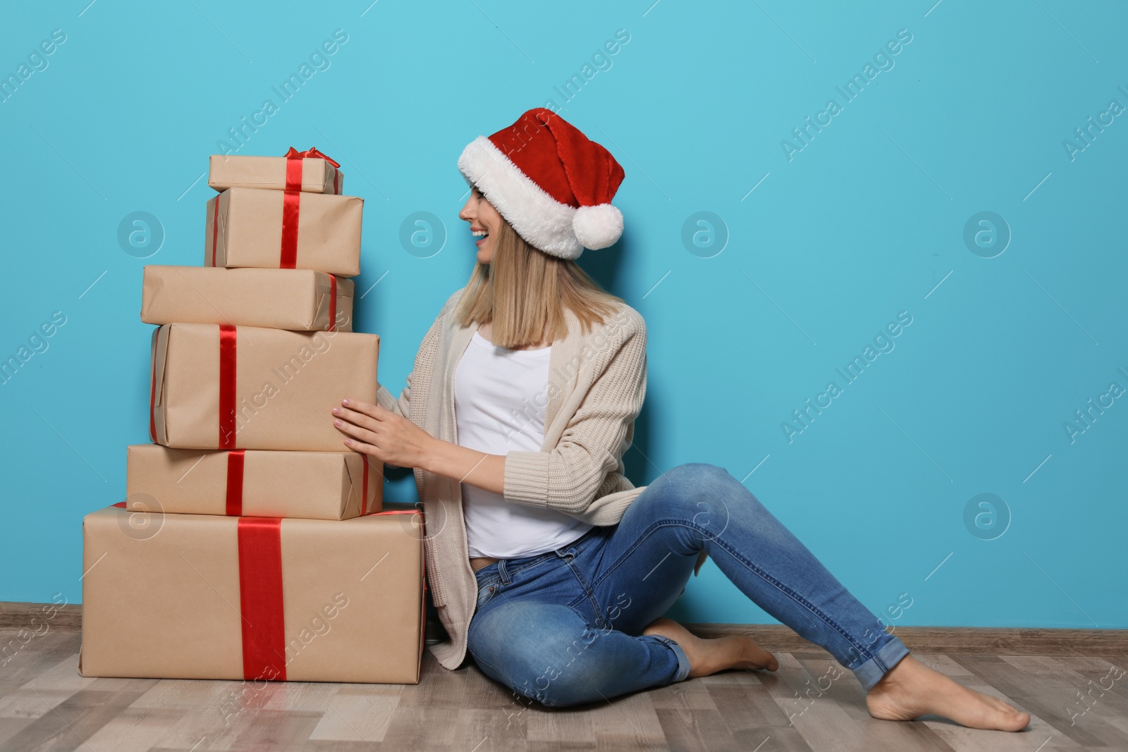 Photo of Young woman with Christmas gifts near color wall