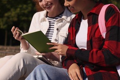 Photo of Young students studying with notebook outdoors, closeup