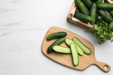 Photo of Fresh ripe cucumbers and parsley on white marble table, flat lay. Space for text