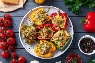 Photo of Flat lay composition with tasty stuffed bell peppers on grey wooden table