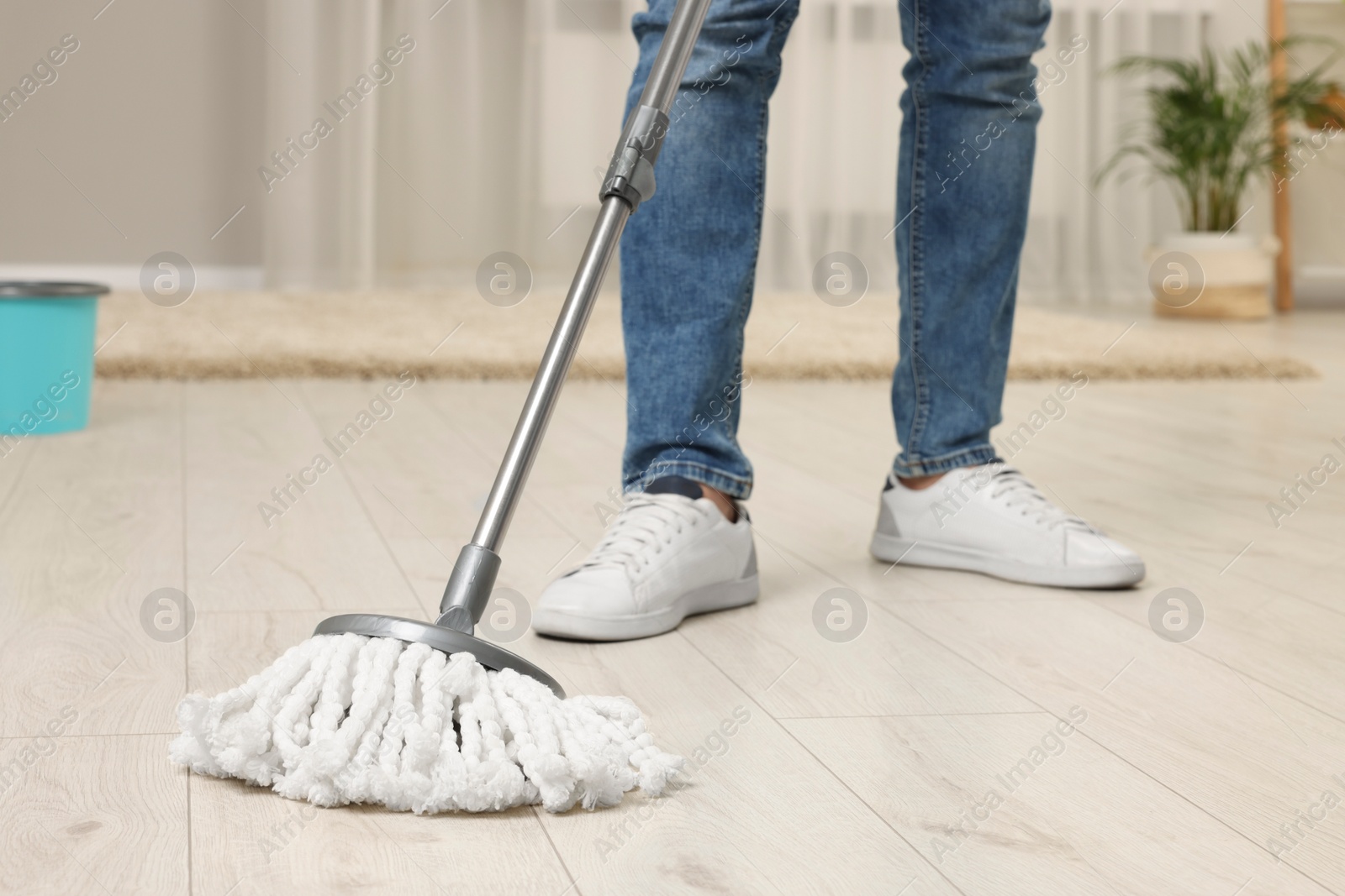 Photo of Man cleaning floor with mop at home, closeup