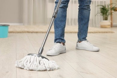 Photo of Man cleaning floor with mop at home, closeup