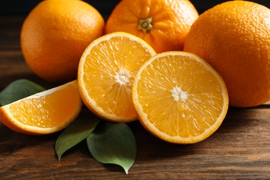 Photo of Fresh oranges with leaves on wooden table, closeup