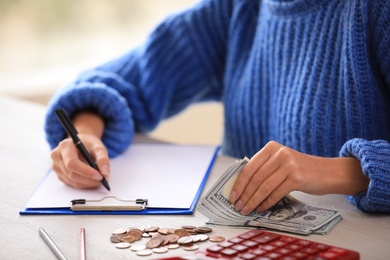 Woman counting money at wooden table, closeup