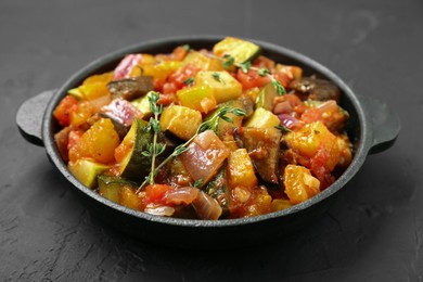 Photo of Dish with tasty ratatouille on black table, closeup