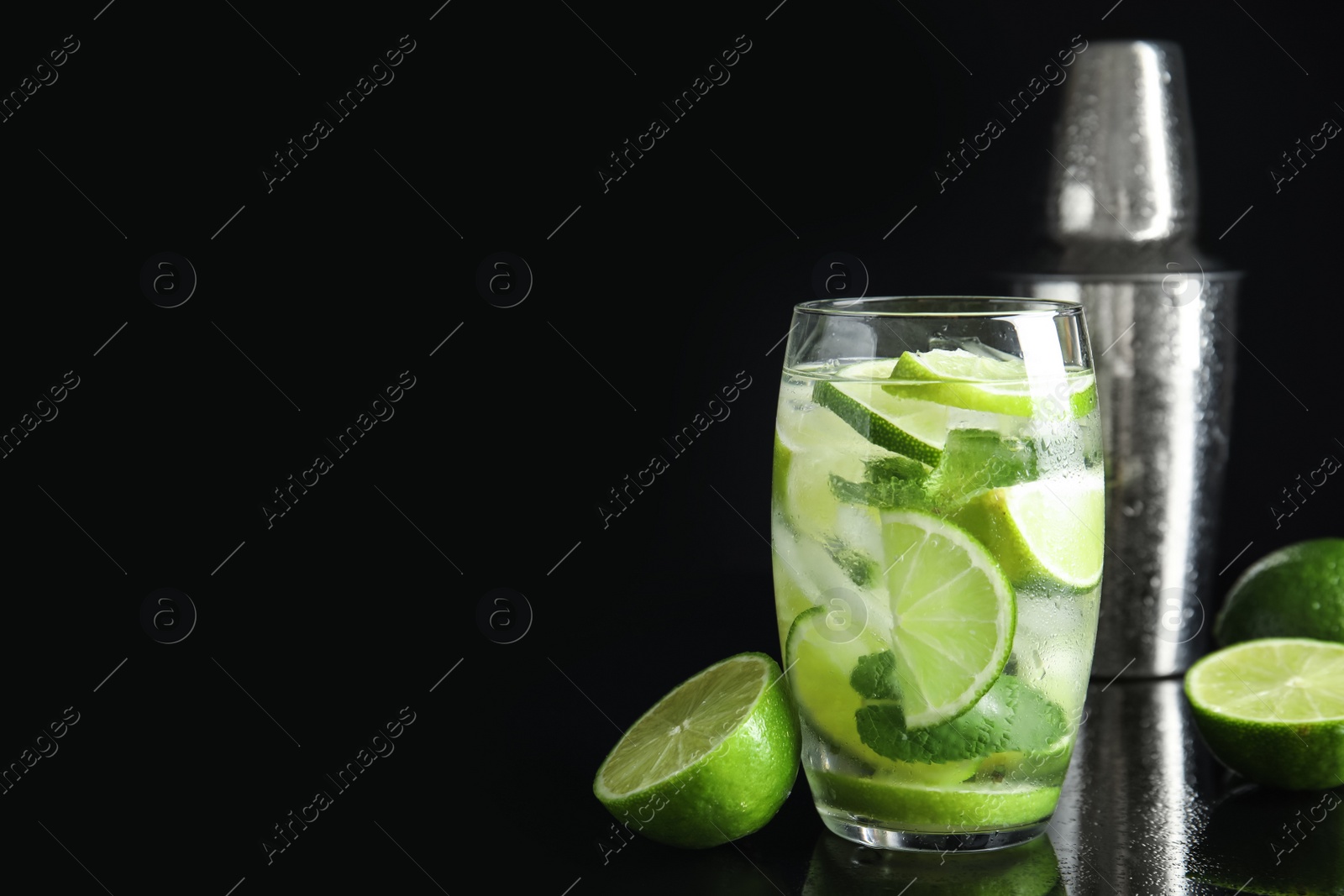 Photo of Delicious mojito and ingredients on black background. Space for text