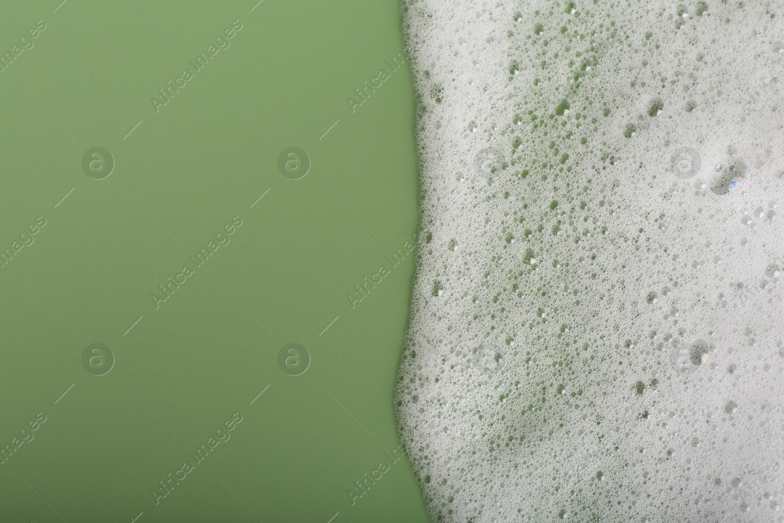 Photo of White fluffy foam on green background, top view. Space for text