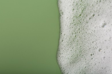 Photo of White fluffy foam on green background, top view. Space for text