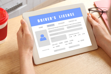 Image of Woman filling in driver's license form online on website using tablet, closeup