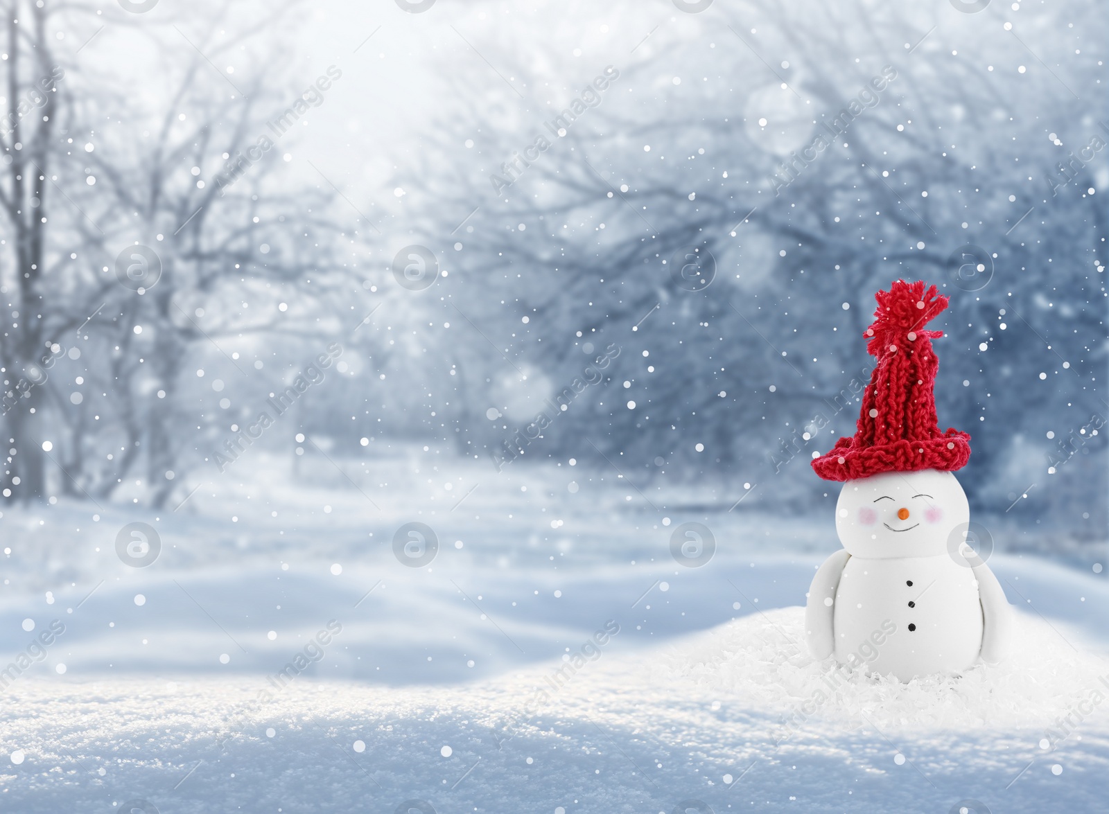 Image of Cute decorative snowman in red hat outdoors on snowy day, space for text