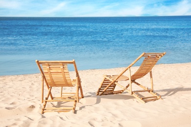 Photo of Wooden deck chairs on sandy beach near sea