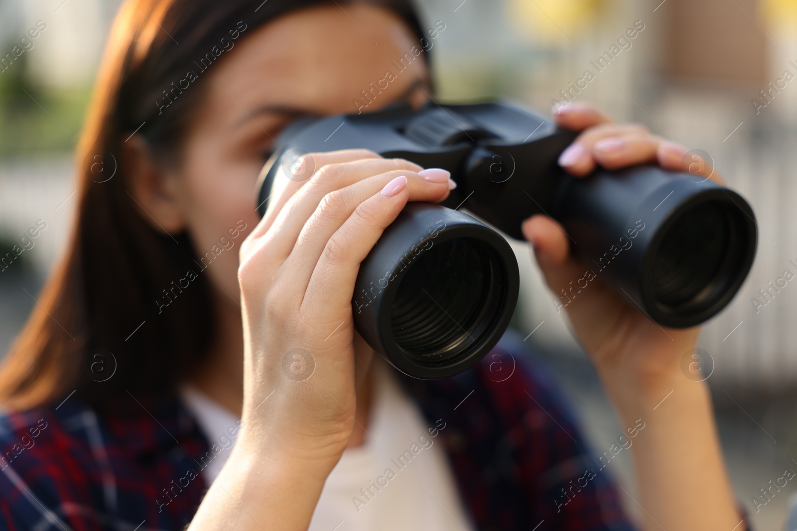 Photo of Concept of private life. Curious young woman with binoculars spying on neighbours outdoors, closeup