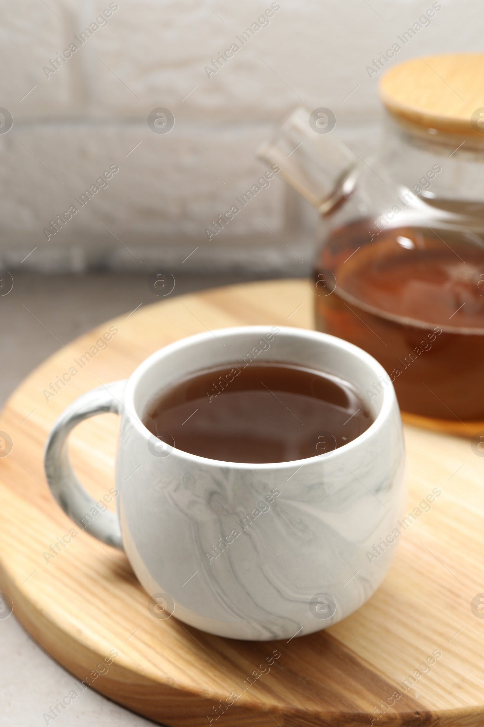 Photo of Aromatic tea in cup and glass teapot on table, closeup