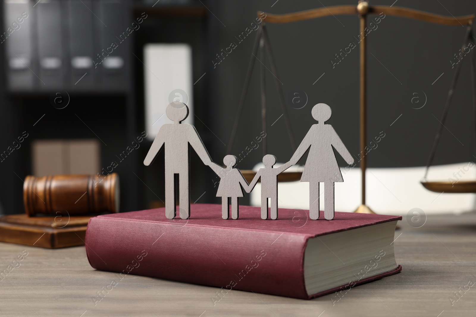 Photo of Family law. Figure of parents with children, book, scales of justice and gavel on wooden table