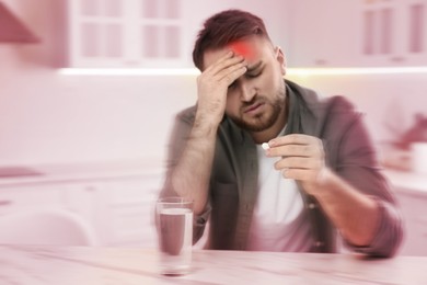 Image of Man with pill suffering from migraine in kitchen