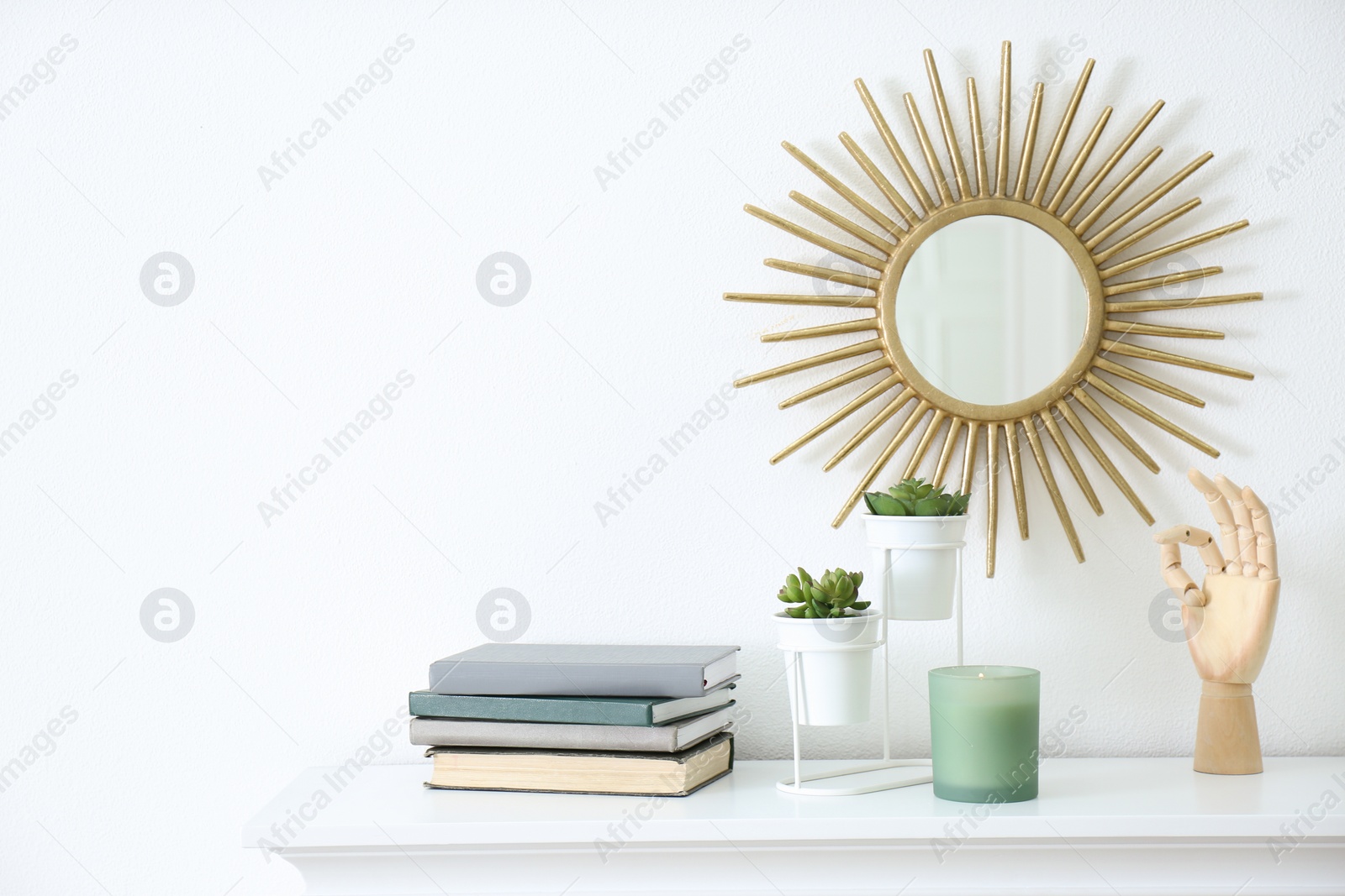 Photo of Burning candle, books and plants on shelf indoors, space for text. Interior elements