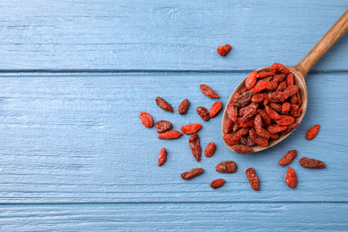 Photo of Dried goji berries on blue wooden table, flat lay. Space for text