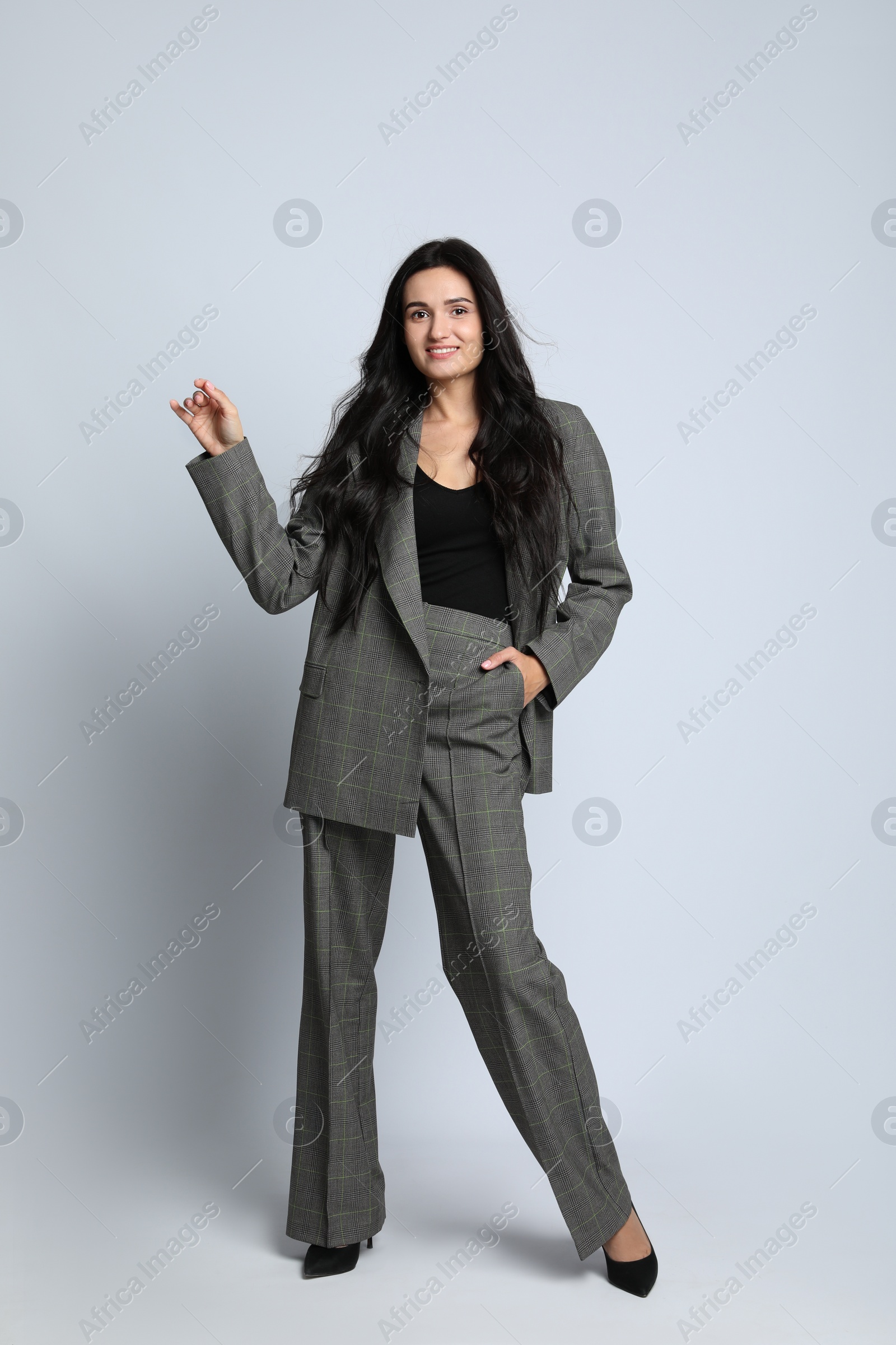 Photo of Full length portrait of beautiful woman in formal suit on light background. Business attire