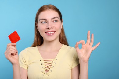 Photo of Woman with condom showing ok gesture on turquoise background. Safe sex