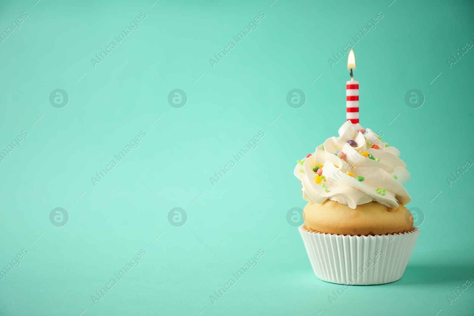 Photo of Delicious birthday cupcake with candle on light green background. Space for text