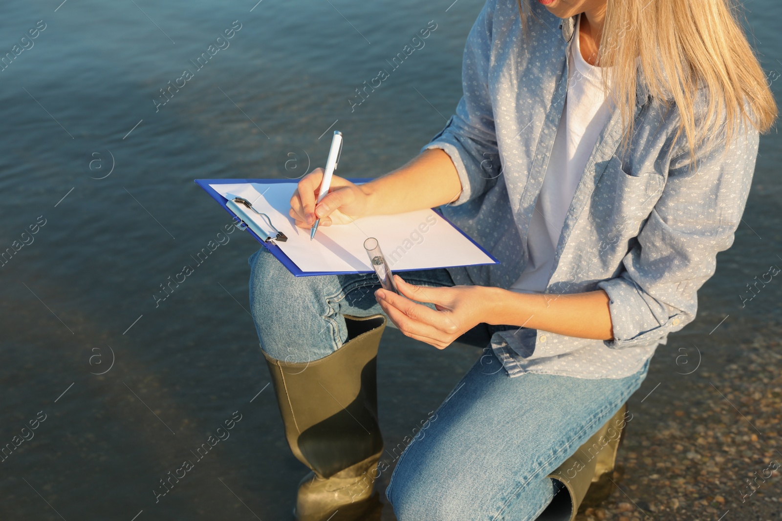 Photo of Scientist with clipboard and sample taken from river, closeup