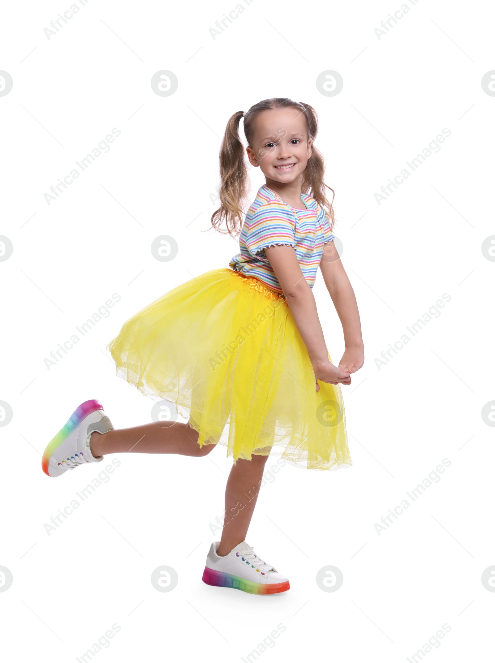Photo of Cute little girl in tutu skirt dancing on white background