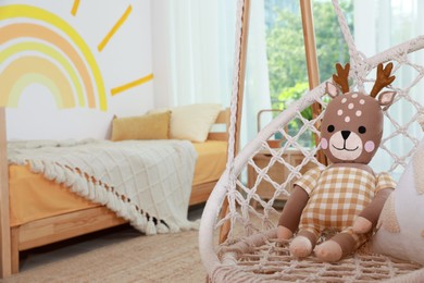 Photo of Swing chair with toy reindeer in child's bedroom, space for text