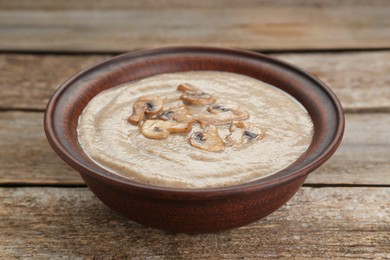 Photo of Delicious mushroom cream soup on wooden table