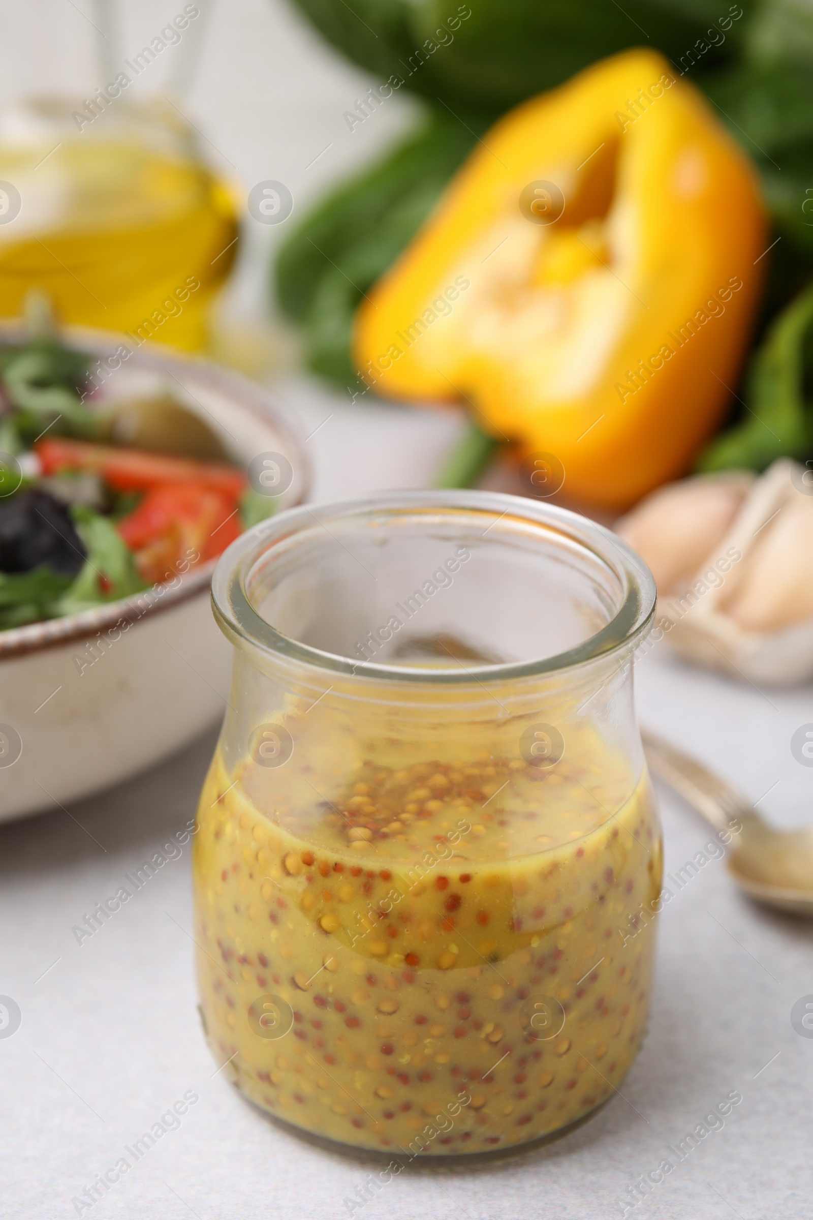 Photo of Tasty vinegar based sauce (Vinaigrette) in jar on light table, closeup