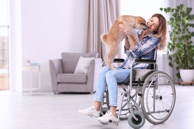 Photo of Young woman in wheelchair with puppy at home