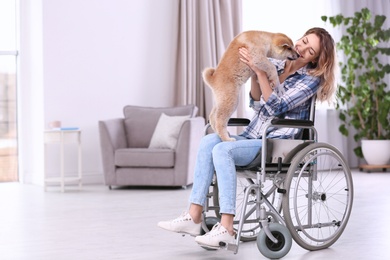 Young woman in wheelchair with puppy at home