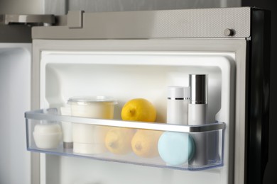 Photo of Different cosmetic products on shelf in refrigerator