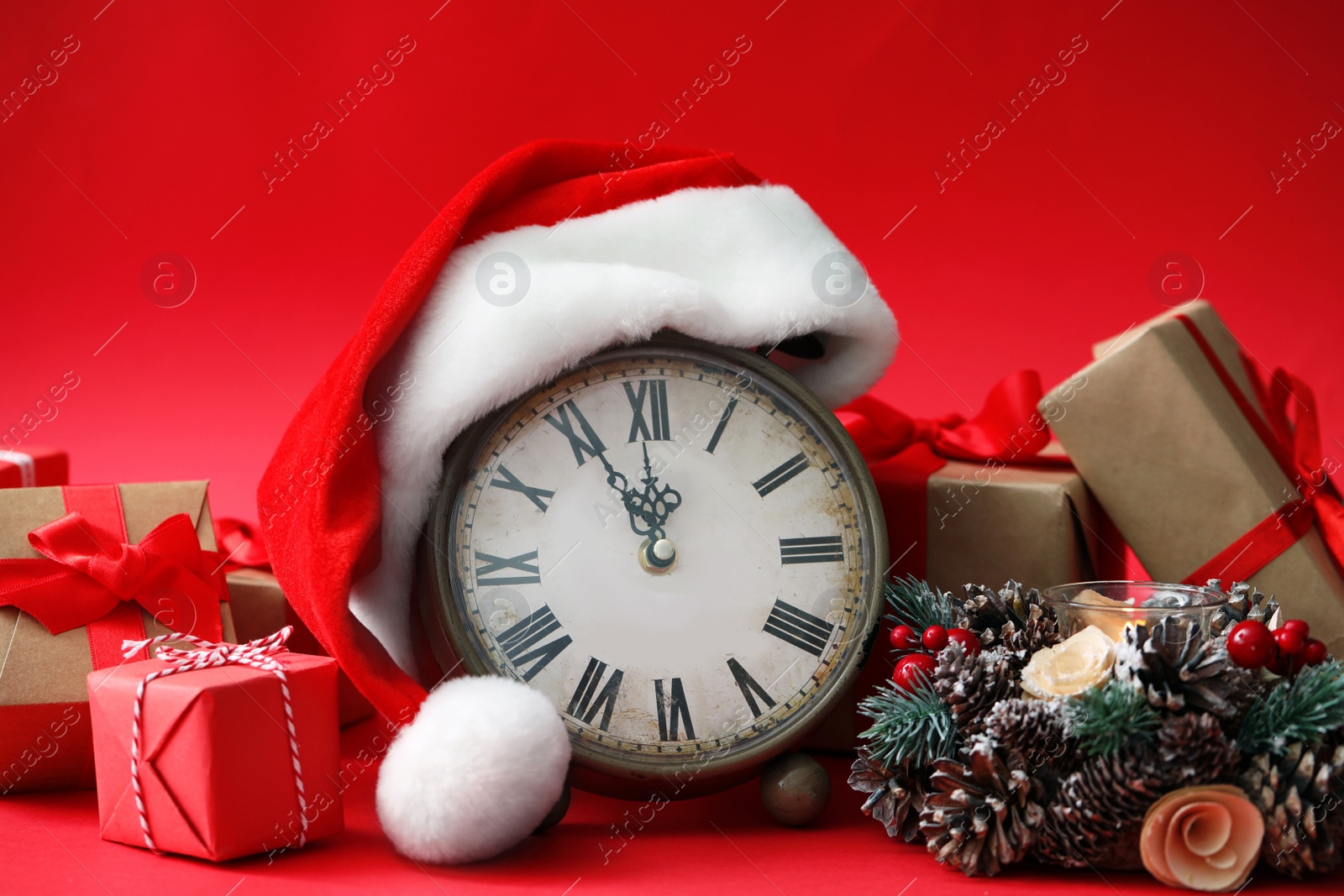 Photo of Alarm clock, gifts and festive decor on red background. New Year countdown