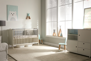 Photo of Cute baby room interior with crib and decor elements