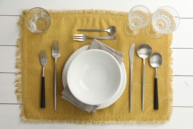 Photo of Stylish setting with cutlery, dishes, glasses and napkin on white wooden table, top view