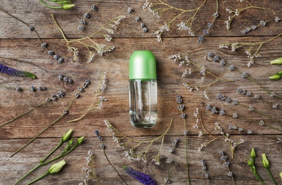 Photo of Natural deodorant and herbs on wooden background