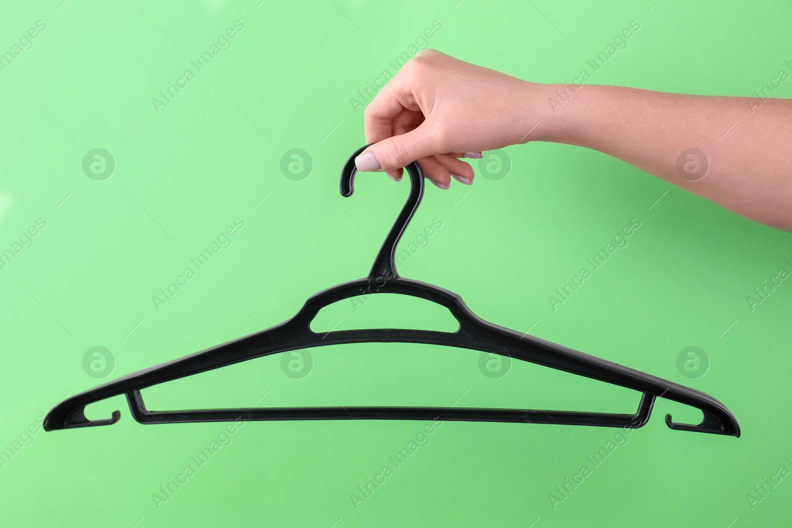 Photo of Woman holding hanger on light green background, closeup