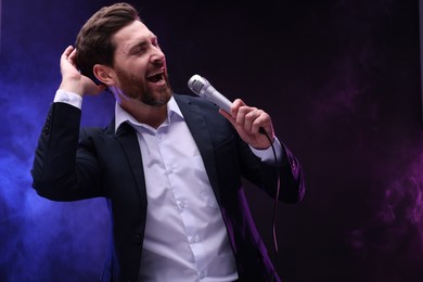 Photo of Emotional man with microphone singing in neon lights. Space for text