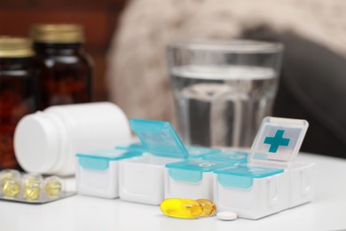 Photo of Plastic pill box with different medicaments on table