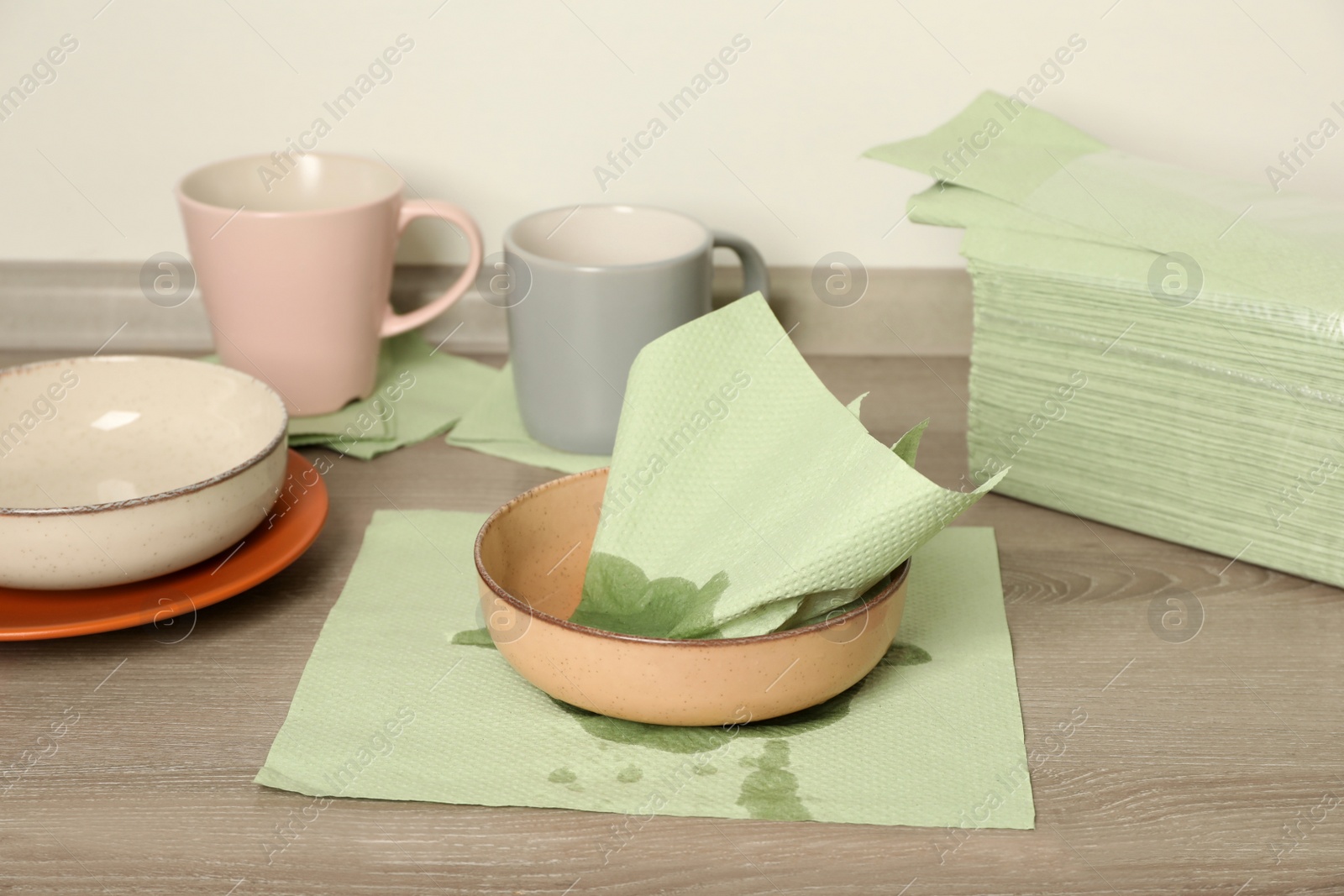 Photo of Wiping bowl with green paper napkin on wooden countertop