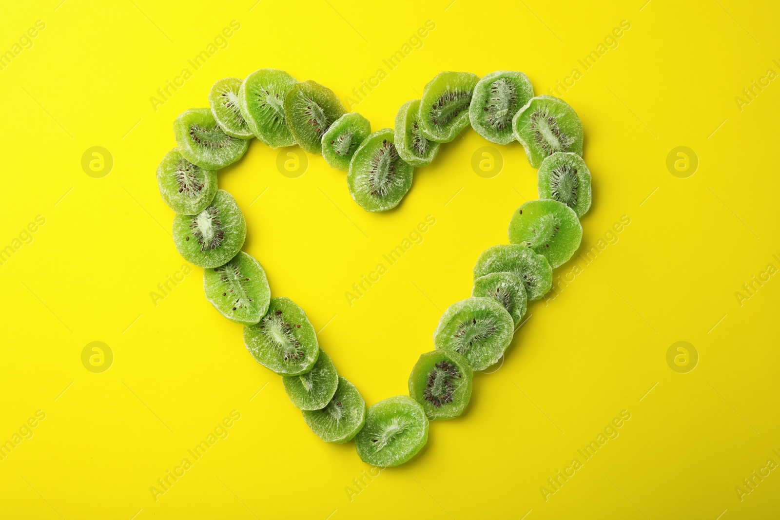 Photo of Heart shaped frame made of kiwi on color background, top view with space for text. Dried fruit as healthy food
