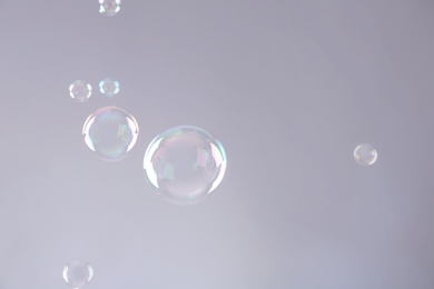 Photo of Beautiful translucent soap bubbles on grey background