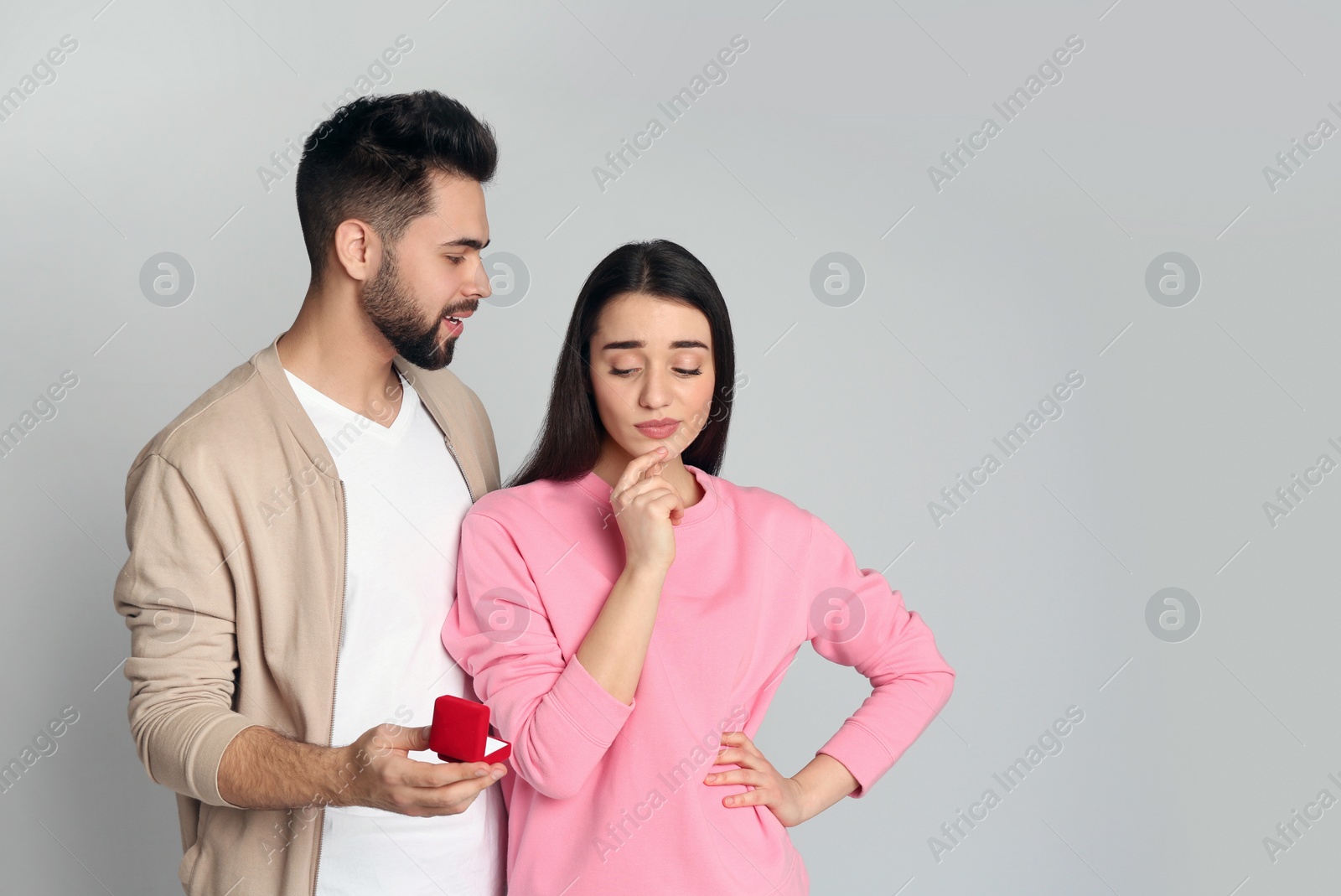 Photo of Man with engagement ring making marriage proposal to girlfriend on light grey background