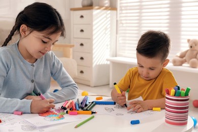 Photo of Cute children coloring drawing at table in room