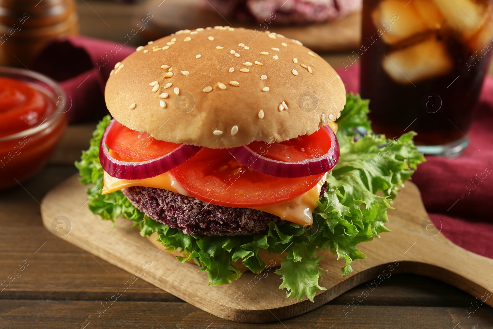 Photo of Tasty vegetarian burger with beet patty, sauce and soda drink on wooden table, closeup