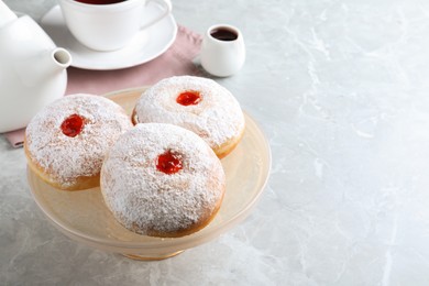 Photo of Pastry stand with delicious jelly donuts on grey table. Space for text