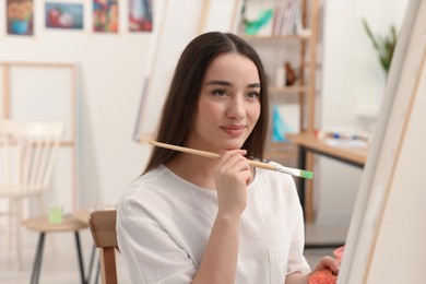 Beautiful young woman painting with brush in studio. Creative hobby